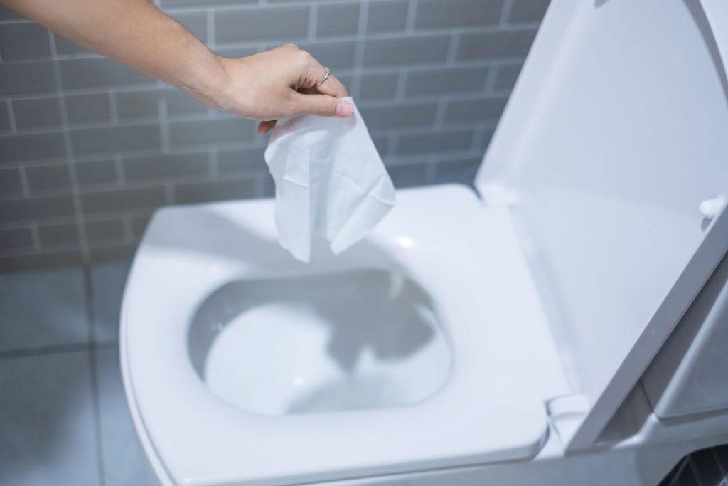 A wipe being flushed, leading to potential plumbing issues.